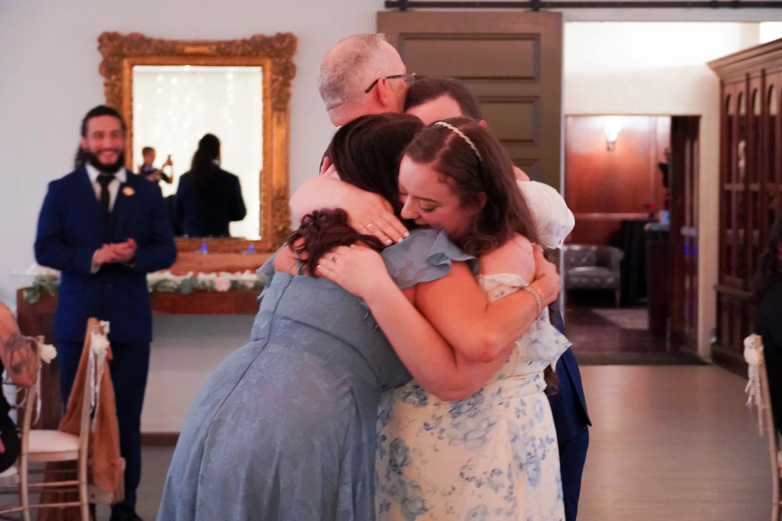 Mother hugs brothers new fiancé. Dad hugs brother. They are all smiling and crying and laughing. A candid moment.