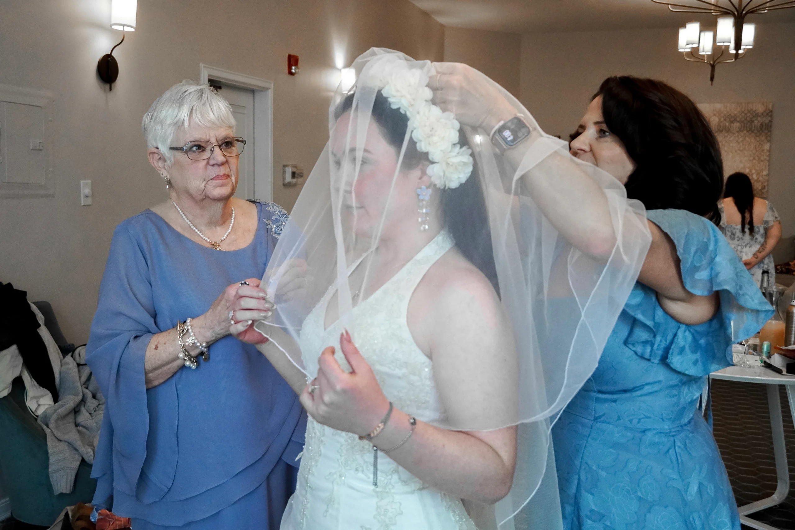 Grandma and mother of the bride help the bride get ready and fix her veil in the dressing room before the wedding ceremony